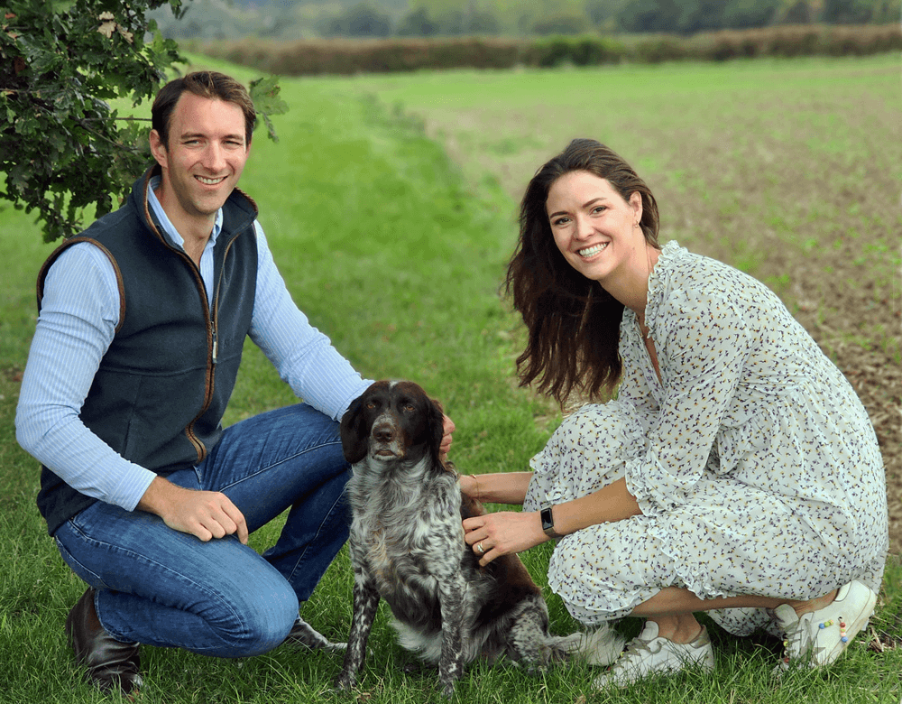 Co-founders James and Jen Mugleston knelling in a field with their dog